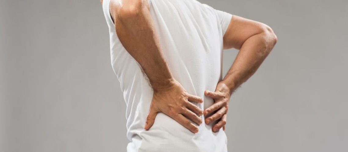 people, healthcare and problem concept - close up of man suffering from pain in back or reins over gray background