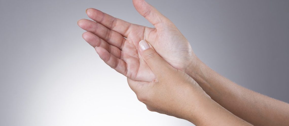 Pain in the joints of the hands on a gray background. Carpal tunnel syndrome. Care of male hands